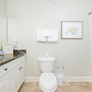 Refreshing guest bathroom featuring a sleek granite countertop, stylish decor, and a convenient tub/shower combo