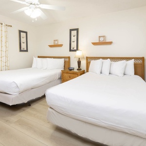 Guest bedroom featuring two double beds with crisp white linens, a nightstand with a lamp, and nautical decor