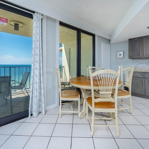 This inviting kitchen features stainless appliances, a cozy dining area, and a breathtaking view from the balcony