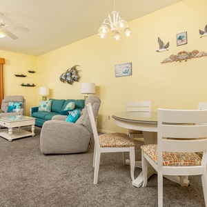 Living area features a turquoise sofa with queen sleeper, cozy chairs, and a dining table, creating a cheerful vibe