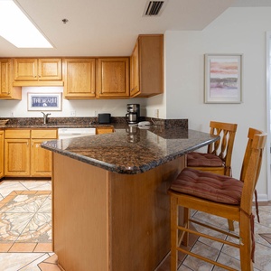Warm wood cabinetry complements the granite countertops in this inviting kitchen, featuring a breakfast bar with seating
