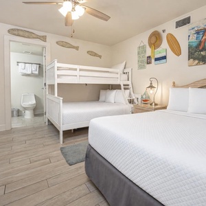 Brightly decorated guest bedroom featuring a double bed and a twin-over-full bunk bed, with beach decor and a cozy vibe