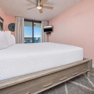 Comfortable king bed and wall-mounted TV in the master suite, with a balcony view inviting relaxation