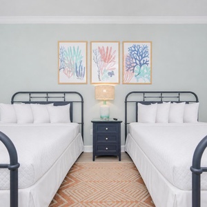 Cheerful guest room featuring queen beds, decorative artwork, and a cozy rug for a delightful stay