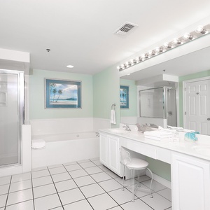 The master bathroom features a spacious vanity, a relaxing soaking tub, and a glass shower, all accented by soft green walls