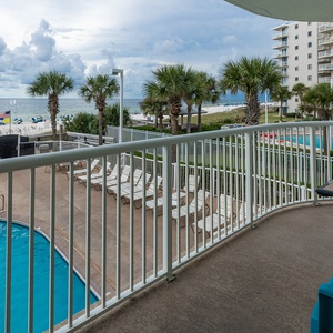 Enjoy a refreshing view from the balcony overlooking the pool and beach, perfect for relaxation in this inviting space