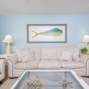 Cozy living area featuring a comfy beige sofa, colorful artwork, and cheerful lamps for a relaxing getaway