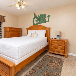 Warm wood furnishings complement the inviting atmosphere of this guest bedroom, featuring a queen bed and decorative wall art
