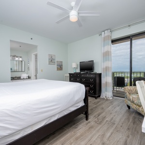 The master bedroom features a comfortable king bed, a TV, and a lovely view through sliding glass doors