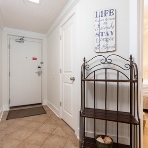 Step into a welcoming entryway adorned with coastal decor, leading to a serene guest bedroom for your relaxing getaway