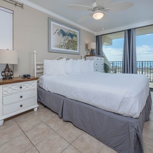 This bedroom features a king-sized bed, coastal decor, and a stunning beachfront view from the large sliding glass doors