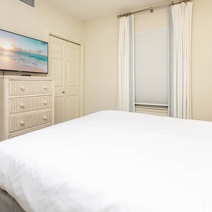 Unwind in this comfortable guest bedroom featuring a queen bed, TV, and charming decor for a restful night's sleep
