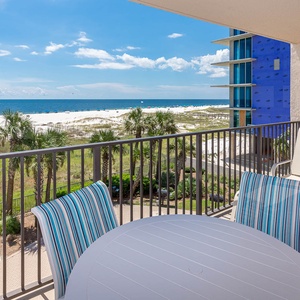 Savor your morning coffee at the balcony table, enjoying views of the beach and gentle waves in the distance
