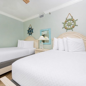 Relax in the tranquil guest bedroom featuring two queen beds and charming nautical decor for a restful stay