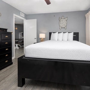 This cozy guest bedroom features a sleek black queen bed, ample storage, and a lovely view through the window