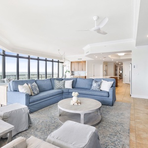 This cozy living area features a blue sectional sofa, a large TV, and stunning views through expansive windows