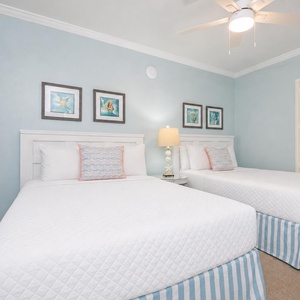 Guest suite with two doubles invites you to rest surrounded by cheerful coral pillows and soft coastal art