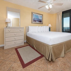 Bright yellow walls complement the king bed and dresser in the master suite, with a balcony view of the beach