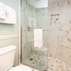 Walk-in shower with elegant marble tiles, plush towels, and a serene color palette for a refreshing experience