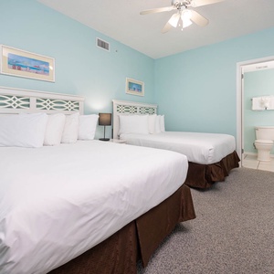 Relax in this bright guest room featuring two comfortable double beds, soft decor, and easy access to the bathroom area