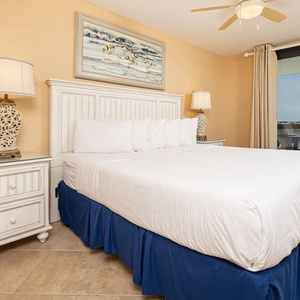 Brightly colored walls in the master suite frame a comfortable king bed, complemented by a lamp and a view of the balcony