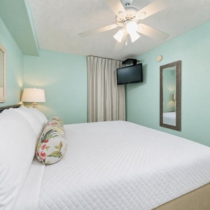 Relax in this calming bedroom suite featuring a king bed, soft lighting, and a TV for your entertainment