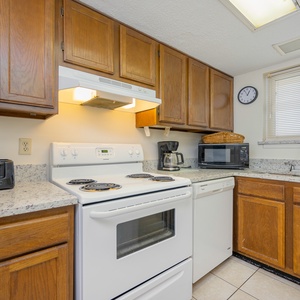 This kitchen features wooden cabinetry, essential appliances, and a cozy atmosphere perfect for meal preparation