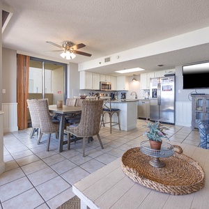 Dining area with woven chairs, a modern kitchen featuring granite countertops, and a cozy seating nook with a TV