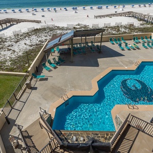 Enjoy the inviting pool area with lounge chairs and a scenic view of the beach, perfect for relaxation and fun