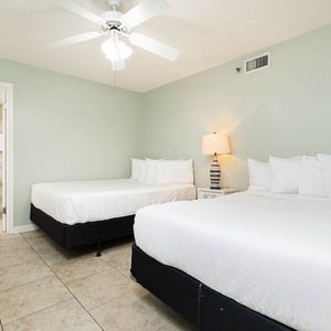 Rest comfortably in this guest room with a queen and a double bed, soft lighting, and a ceiling fan