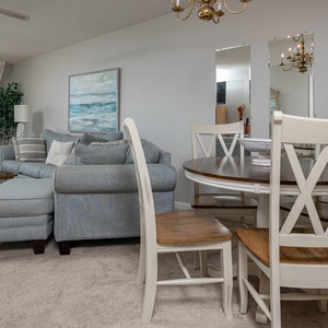 Unwind in the inviting living area, featuring a queen sofa sleeper, dining table, and beautiful coastal artwork