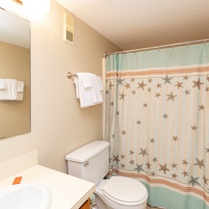 The bathroom features a bright, inviting space with a starfish-patterned shower curtain and ample fresh towels