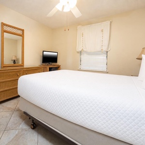 Cozy guest bedroom features a queen bed, a dresser with a mirror, and a TV, creating a welcoming retreat for relaxation