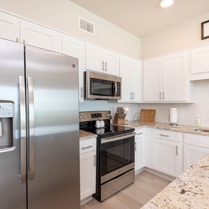 This kitchen features modern stainless appliances, granite countertops, and a bright, inviting atmosphere perfect for cooking