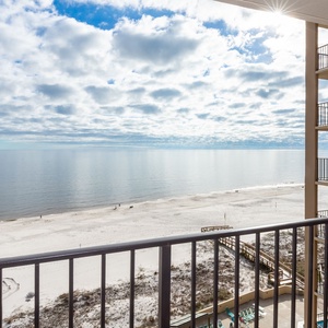 Breathtaking view of the serene beach and calm waters from a private balcony, perfect for relaxation and unwinding