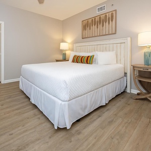 Rest in this comfortable guest bedroom featuring a king bed, colorful accent pillows, and stylish decor