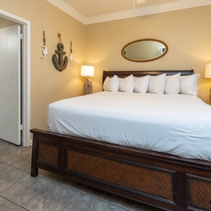 A cozy guest bedroom features a king bed with plush pillows, nautical decor, and soft lighting for a relaxing atmosphere