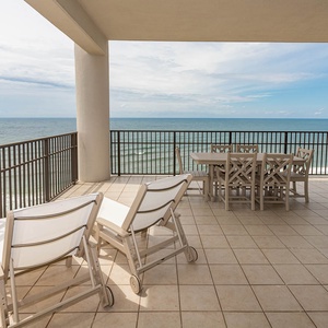 This wrap-around balcony features comfortable lounge chairs and outdoor dining, offering beachfront views for relaxation