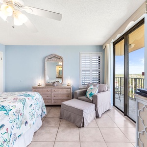 Brightly decorated master bedroom features a king bed, cozy seating area, and sliding glass doors leading to a balcony