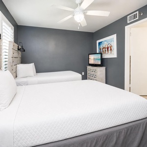 Unwind in the comfortable guest bedroom featuring two twin beds with soft bedding, stylish decor, and a TV