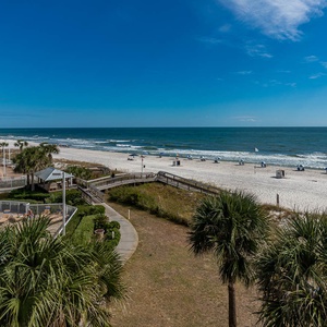 Enjoy stunning beach views from the balcony, with a pool below and inviting lounge chairs lining the shore