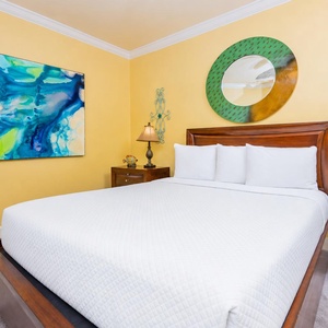 Unwind in this cheerful guest bedroom with a comfortable queen bed, vibrant yellow walls, and colorful art
