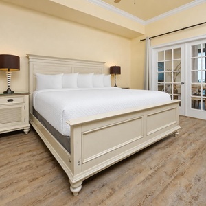 Soothing master bedroom featuring a plush king bed and elegant French doors leading to a scenic dining and balcony view