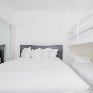 Bright and airy bedroom featuring a cozy queen bed and a stylish twin bunk bed, perfect for family or group stays