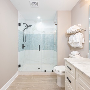 Experience a refreshing shower in the guest bath featuring elegant tile accents and soft towels