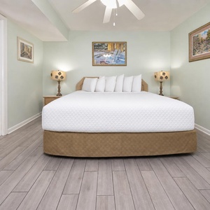 A spacious bedroom features a large king bed with multiple pillows, two decorative lamps, and an adjoining bathroom