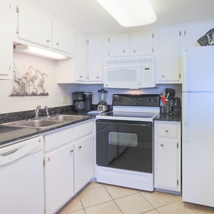 This kitchen features white cabinetry, sleek countertops, and essential appliances for a delightful cooking experience