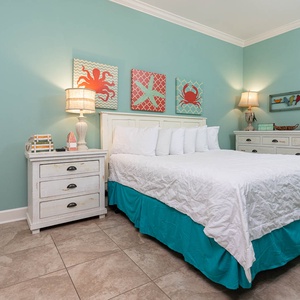 This bright guest bedroom features a king bed, aqua accents, and cheerful coastal decor for a refreshing retreat