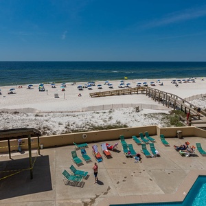 This inviting beach view showcases a vibrant pool area with lounge chairs, perfect for relaxing under the sun