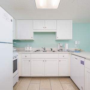 Cook your favorite meals in this kitchen featuring white cabinets, a spacious countertop, and essential appliances